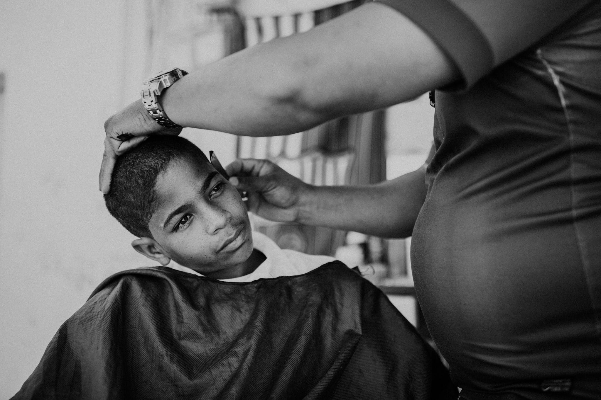 Black and white portrait of a young boy at the barbershop in Vinales, Cuba. Wedding and travel photographer Brent Calis.