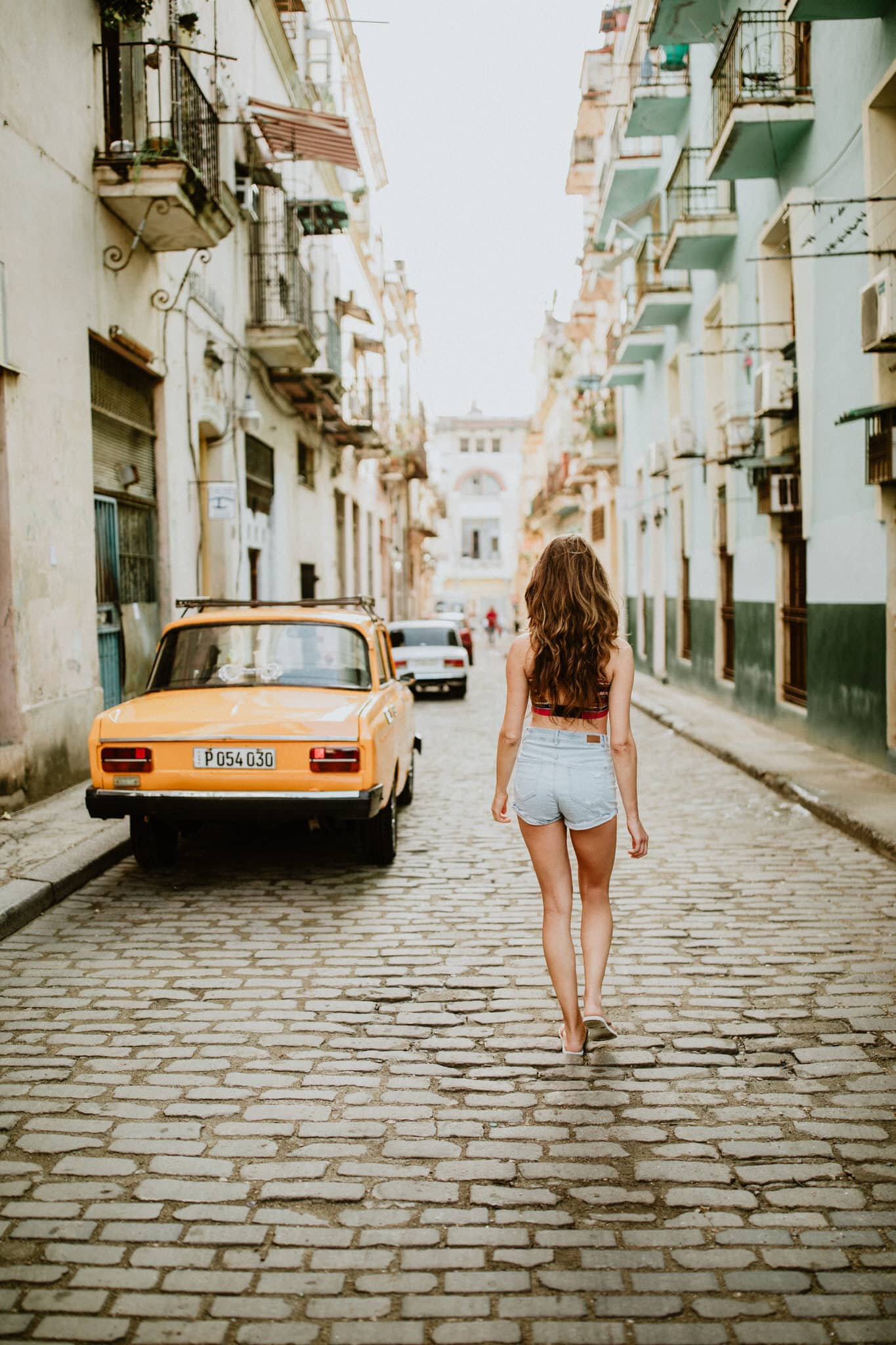 Yellow old car havana Cuba, cobble stone, tourist walking