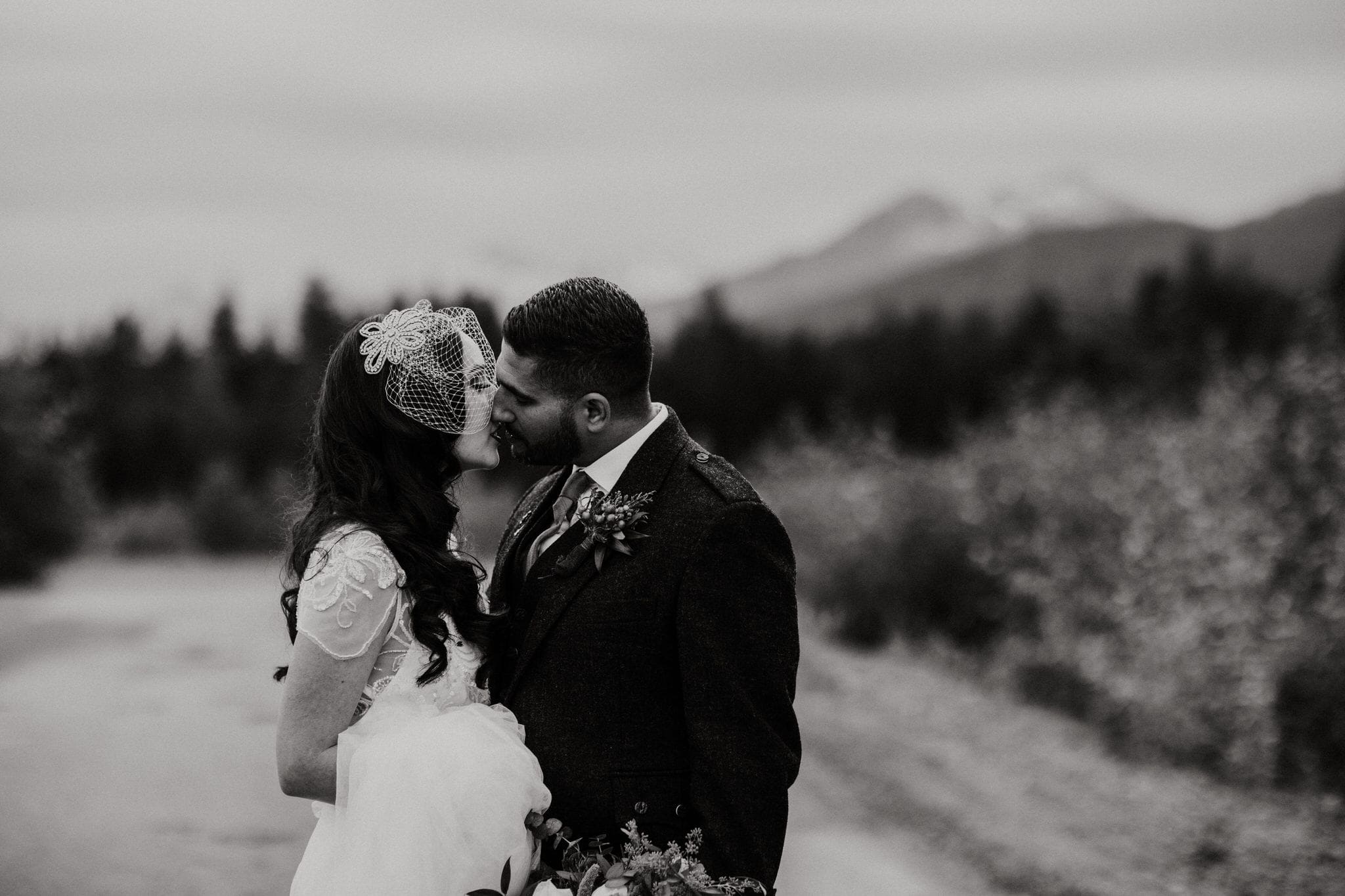 Black and white photo of bride and groom kissing in the mountains of Whistler. Destination wedding photographer Brent Calis.