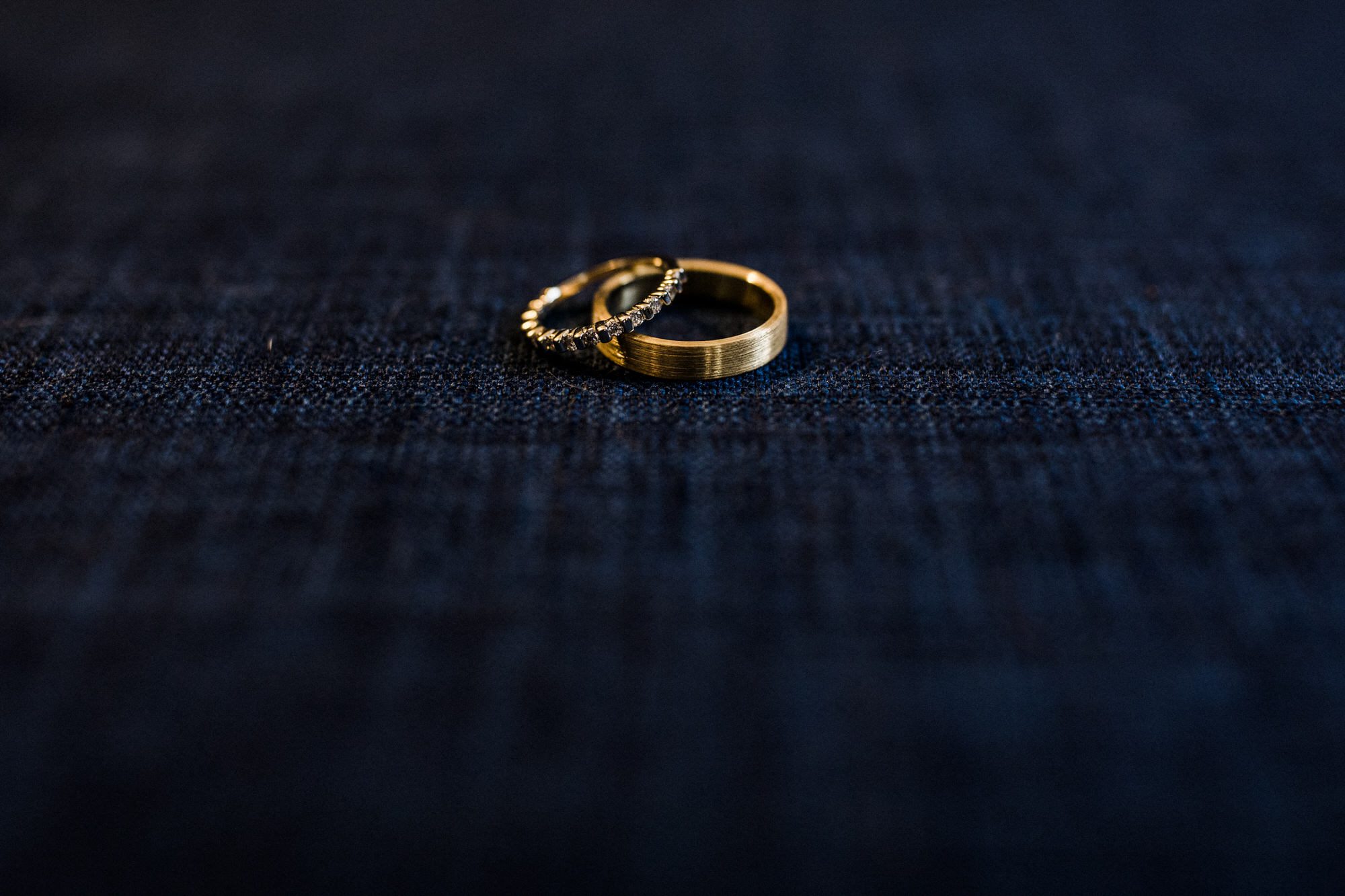 Gold wedding rings sitting on jeans. Destination wedding photographer Brent Calis.
