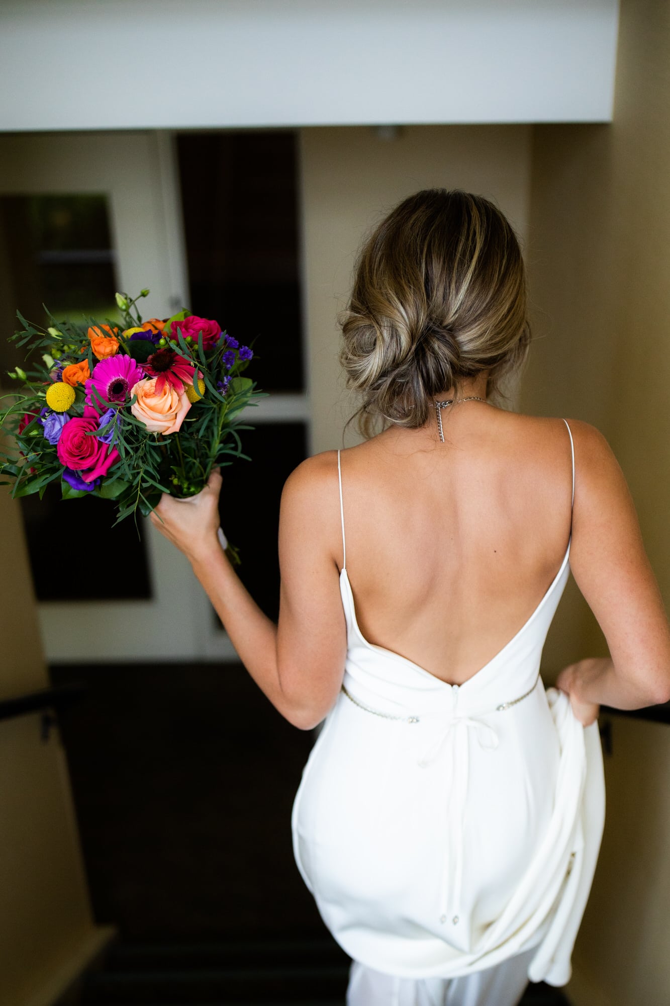 Back shot of bride walking down the stairs with boquet. Destination wedding photographer Brent Calis.